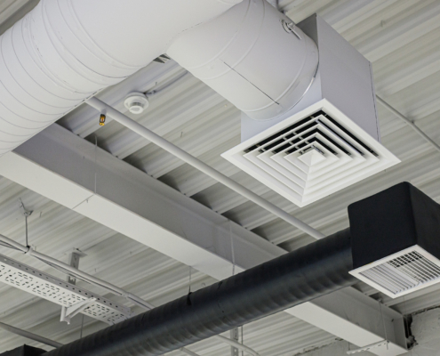 Two ventilation duct systems with grilles under ceiling in commercial building
